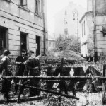 Grupa powstańców przy barykadzie zamykającej ul. Barokową